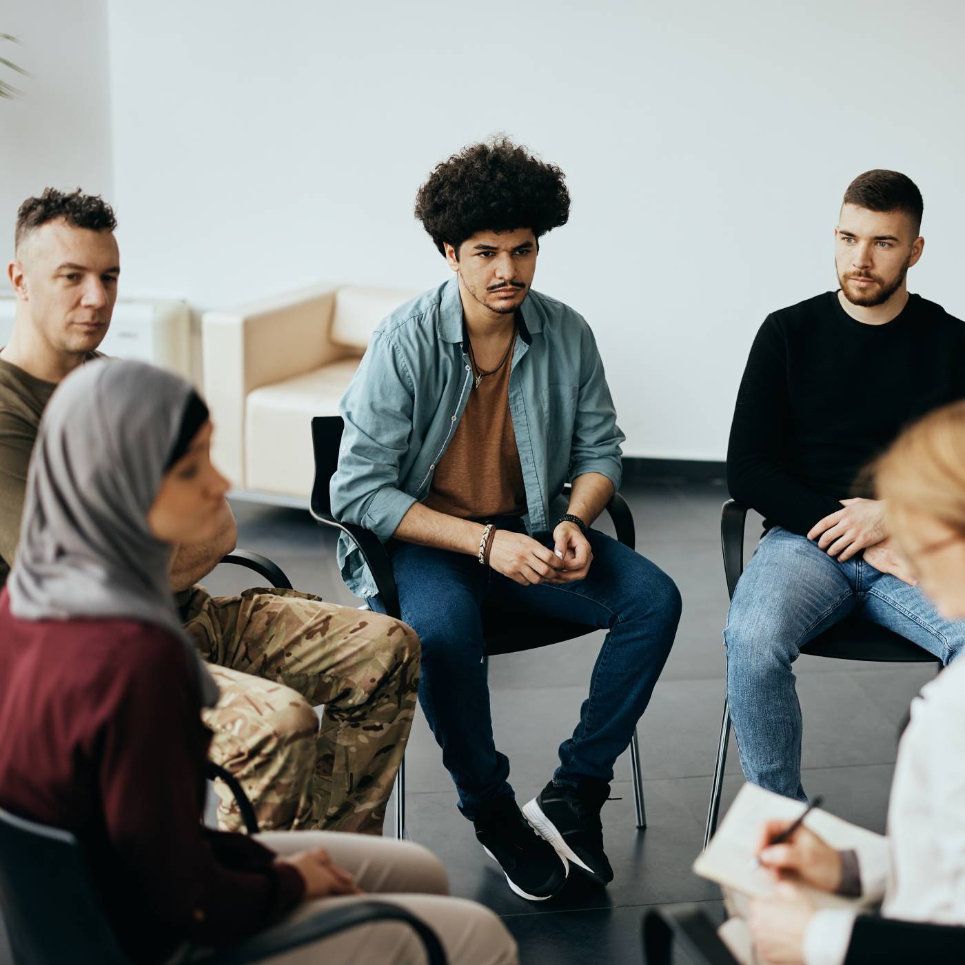 Diverse group of adults sitting in a circle during a group therapy or support session.