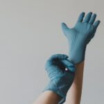 Cropped hands putting on blue rubber gloves